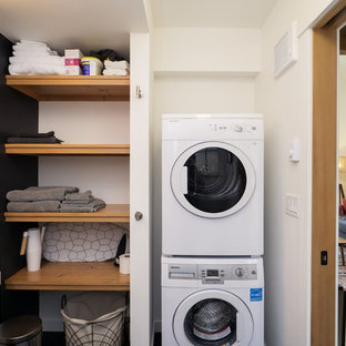 ポートランドのカントリー風おしゃれな家事室 (一体型シンク、黒い壁、上下配置の洗濯機・乾燥機) の写真