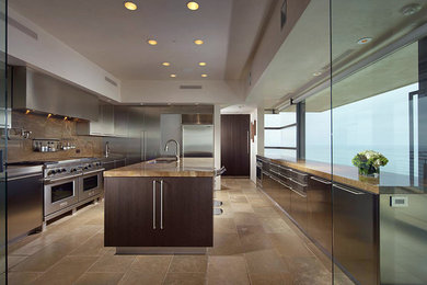 Contemporary u-shaped separate kitchen in Los Angeles with an undermount sink, flat-panel cabinets, dark wood cabinets, granite benchtops, stainless steel appliances, limestone floors and with island.