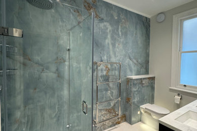Photo of a medium sized contemporary shower room bathroom in London with black cabinets, a corner shower, a one-piece toilet, porcelain tiles, an integrated sink, solid surface worktops, multi-coloured worktops, double sinks and a freestanding vanity unit.