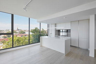 This is an example of a modern open plan kitchen in Melbourne with glass-front cabinets and with island.