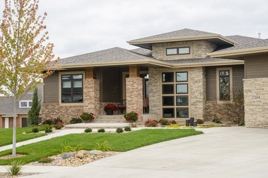Example of a mid-sized transitional multicolored one-story mixed siding house exterior design in Other with a hip roof and a shingle roof