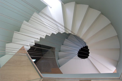 Diseño de escalera curva actual de tamaño medio con escalones de metal, contrahuellas de metal y barandilla de cable