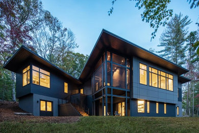 Mid-sized transitional gray two-story wood house exterior photo in Other with a shed roof and a metal roof