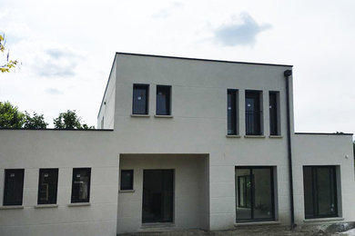 Réalisation d'une façade de maison de ville blanche design de taille moyenne et à un étage avec un revêtement mixte et un toit plat.