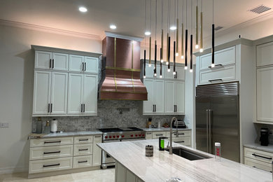 Inspiration for a mid-sized modern l-shaped ceramic tile, beige floor and tray ceiling eat-in kitchen remodel in Orlando with a drop-in sink, recessed-panel cabinets, white cabinets, marble countertops, gray backsplash, ceramic backsplash, stainless steel appliances, an island and white countertops