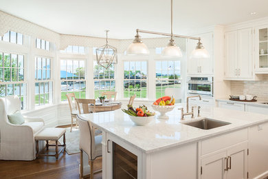 Mid-sized elegant medium tone wood floor enclosed kitchen photo in New York with white cabinets, granite countertops, white backsplash, ceramic backsplash, stainless steel appliances and an island