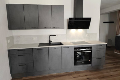 Offene, Mittelgroße Moderne Küche mit Einbauwaschbecken, schwarzen Elektrogeräten, Laminat und braunem Boden in Sonstige