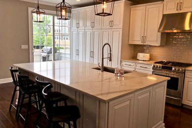 Example of a large classic l-shaped dark wood floor and brown floor open concept kitchen design in Chicago with a single-bowl sink, raised-panel cabinets, white cabinets, quartz countertops, gray backsplash, ceramic backsplash, stainless steel appliances, an island and white countertops