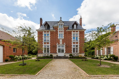 Traditional three-storey brick house exterior in Paris with a hip roof and a shingle roof.