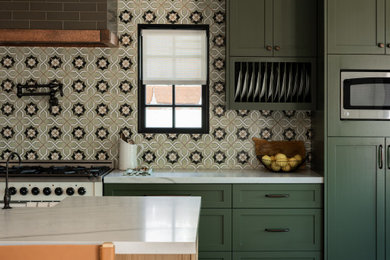 Eat-in kitchen - mid-sized country medium tone wood floor eat-in kitchen idea in Orange County with a farmhouse sink, shaker cabinets, green cabinets, quartzite countertops, green backsplash, ceramic backsplash, paneled appliances, an island and gray countertops