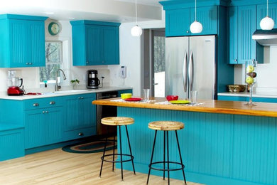 Inspiration for a mid-sized transitional u-shaped light wood floor kitchen remodel in Orange County with an undermount sink, shaker cabinets, blue cabinets, solid surface countertops, stainless steel appliances and an island