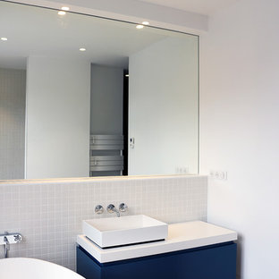 Ispirazione per una piccola stanza da bagno con doccia minimalista con ante blu, vasca da incasso, doccia aperta, WC sospeso, piastrelle bianche, piastrelle in ceramica, pareti blu, parquet chiaro, lavabo a bacinella, top in legno, pavimento beige, doccia aperta e top blu