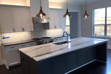 Mid-sized transitional single-wall dark wood floor open concept kitchen photo in Dallas with recessed-panel cabinets, white cabinets, marble countertops, white backsplash, stone tile backsplash, stainless steel appliances and an island