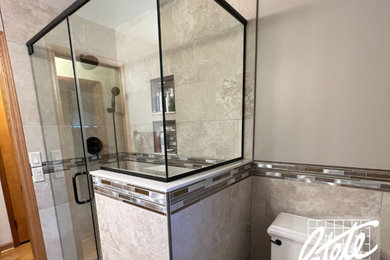 Inspiration for a mid-sized timeless beige tile and stone slab wood-look tile floor, brown floor and single-sink bathroom remodel with brown cabinets, a one-piece toilet, beige walls, quartzite countertops, a hinged shower door and beige countertops