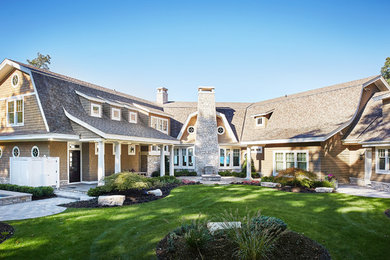 Example of a large beach style beige mixed siding exterior home design in Grand Rapids with a gambrel roof