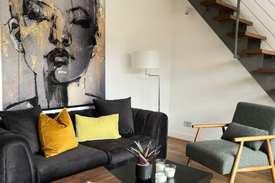 Photo of a large industrial open plan living room in London with white walls and medium hardwood flooring.