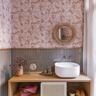 Imagen de cuarto de baño único, flotante y papel pintado, actual, papel pintado, con armarios abiertos, puertas de armario de madera oscura, baldosas y/o azulejos grises, paredes rosas, lavabo sobreencimera, suelo multicolor, encimeras marrones y papel pintado