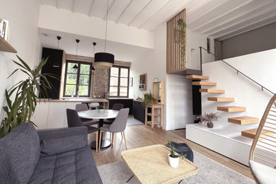 Foto de sala de estar contemporánea sin chimenea con paredes blancas, suelo de madera clara y vigas vistas