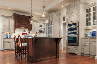 Inspiration for a large timeless u-shaped dark wood floor enclosed kitchen remodel in Other with an undermount sink, shaker cabinets, beige cabinets, granite countertops, white backsplash, stone tile backsplash, stainless steel appliances and an island