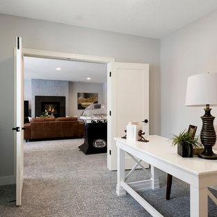 Diseño de sótano con ventanas moderno, de tamaño medio, con paredes grises, moqueta, chimenea lineal, marco de chimenea de hormigón y suelo gris