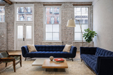Inspiration for an industrial medium tone wood floor, brown floor, exposed beam and brick wall living room remodel in New York with gray walls