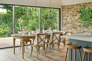 This is an example of a large contemporary open plan dining room in Hampshire with white walls and light hardwood flooring.
