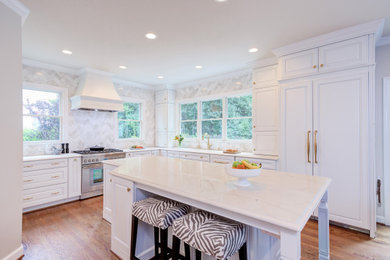 Inspiration for a large traditional l-shaped kitchen/diner in Raleigh with a submerged sink, beaded cabinets, white cabinets, engineered stone countertops, white splashback, marble splashback, integrated appliances, medium hardwood flooring, an island, brown floors and white worktops.