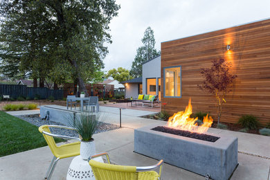 Example of a large 1950s backyard concrete patio design in San Francisco with a fire pit and no cover