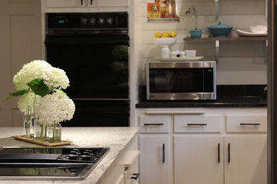 Mid-sized farmhouse l-shaped medium tone wood floor and brown floor enclosed kitchen photo in Milwaukee with a single-bowl sink, flat-panel cabinets, white cabinets, granite countertops, white backsplash, wood backsplash, stainless steel appliances and an island