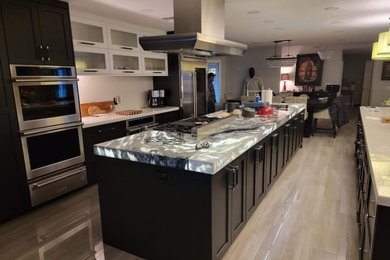 Example of a large trendy galley porcelain tile and gray floor eat-in kitchen design in Las Vegas with an integrated sink, shaker cabinets, black cabinets, quartz countertops, white backsplash, quartz backsplash, stainless steel appliances, two islands and gray countertops