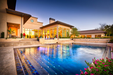 Large minimalist backyard custom-shaped and stone infinity hot tub photo in Denver