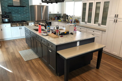 Large transitional l-shaped laminate floor and brown floor eat-in kitchen photo in Denver with an undermount sink, shaker cabinets, white cabinets, granite countertops, blue backsplash, ceramic backsplash, stainless steel appliances, an island and gray countertops