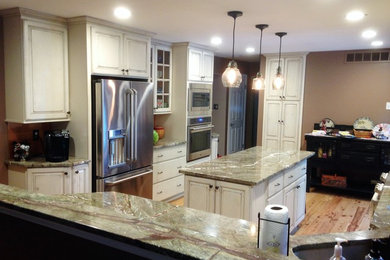 Inspiration for a large u-shaped eat-in kitchen remodel in Philadelphia with raised-panel cabinets, distressed cabinets, granite countertops, metallic backsplash, metal backsplash, stainless steel appliances and an island