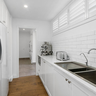 ゴールドコーストの大きいトラディショナルスタイルのおしゃれなランドリールーム (アンダーカウンターシンク、シェーカースタイル扉のキャビネット、白いキャビネット、クオーツストーンカウンター、リノリウムの床、茶色い床、黄色いキッチンカウンター) の写真