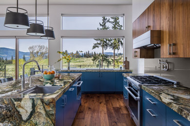Mid-sized modern galley open plan kitchen in Portland with an undermount sink, flat-panel cabinets, blue cabinets, granite benchtops, brown splashback, glass sheet splashback, stainless steel appliances, medium hardwood floors, with island and multi-coloured benchtop.