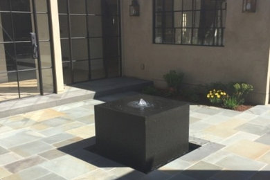 This is an example of a transitional courtyard formal garden in San Francisco with a water feature and natural stone pavers.