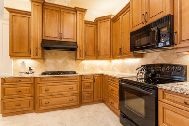 Example of a classic u-shaped porcelain tile kitchen design in Jacksonville with an undermount sink, raised-panel cabinets, medium tone wood cabinets, granite countertops, beige backsplash, ceramic backsplash, black appliances and no island