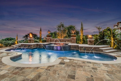 Inspiration for a large contemporary backyard custom-shaped pool in Orange County with a hot tub and natural stone pavers.