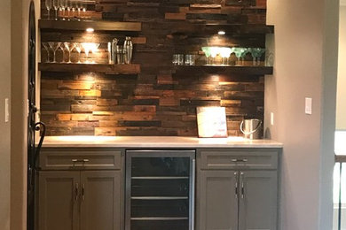 Design ideas for a mid-sized transitional home bar in Dallas with shaker cabinets, grey cabinets, quartz benchtops, brown splashback, timber splashback, dark hardwood floors and beige benchtop.