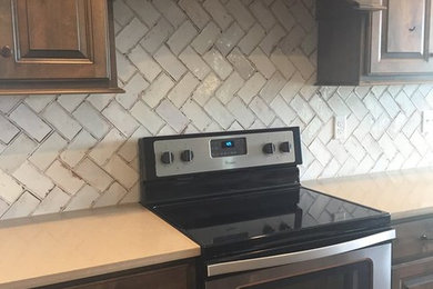 Eat-in kitchen - mid-sized rustic l-shaped dark wood floor and brown floor eat-in kitchen idea in Other with raised-panel cabinets, quartz countertops, an island, a farmhouse sink, dark wood cabinets, white backsplash, subway tile backsplash, stainless steel appliances and beige countertops