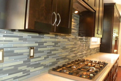 Kitchen pantry - large transitional u-shaped dark wood floor kitchen pantry idea in New York with recessed-panel cabinets, dark wood cabinets, laminate countertops, blue backsplash, an undermount sink, ceramic backsplash, stainless steel appliances and a peninsula