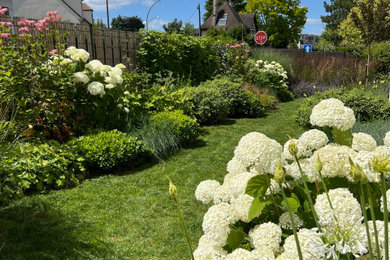 Cette photo montre un jardin avant nature de taille moyenne avec une exposition ensoleillée, un massif de fleurs et une clôture en bois.