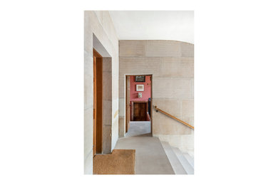 他の地域にあるラグジュアリーな広いおしゃれな玄関ホール (ベージュの壁、ライムストーンの床、茶色いドア、ベージュの床) の写真