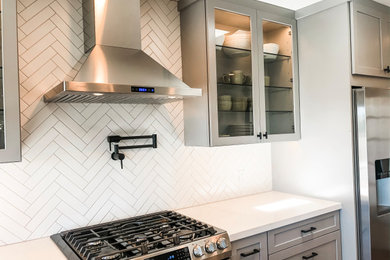Example of a large 1950s u-shaped dark wood floor and brown floor eat-in kitchen design in San Francisco with an undermount sink, shaker cabinets, gray cabinets, quartz countertops, white backsplash, ceramic backsplash, stainless steel appliances, an island and white countertops