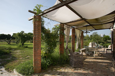 This is an example of a mid-sized country front yard verandah in Venice with natural stone pavers and an awning.
