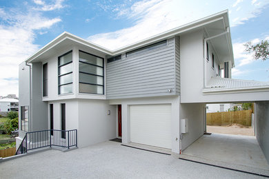 Photo of a mid-sized tropical three-storey brick grey house exterior in Brisbane with a flat roof and a metal roof.