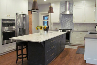 Design ideas for a large country eat-in kitchen in DC Metro with an undermount sink, shaker cabinets, blue cabinets, quartz benchtops, white splashback, subway tile splashback, stainless steel appliances, medium hardwood floors, with island, brown floor and white benchtop.