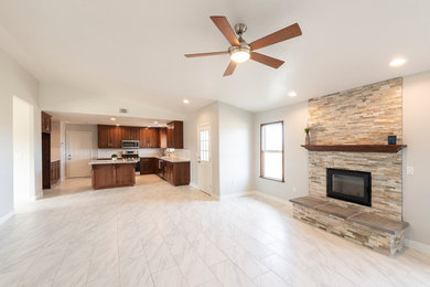 Example of a mid-sized arts and crafts open concept porcelain tile and white floor family room design in Los Angeles with gray walls, a wood stove and a stone fireplace