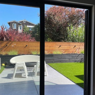 The patio and planter bed stretch across the yard, giving a sense of space.