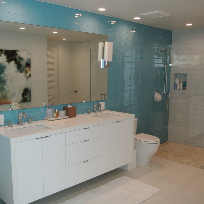 Master bathroom with gorgeous blue tiled walls.   White High Gloss floating cabinetry with undercount sinks.  White Cambria Counter tops.  Large shower enclosure with shampoo niche.  White glass showe